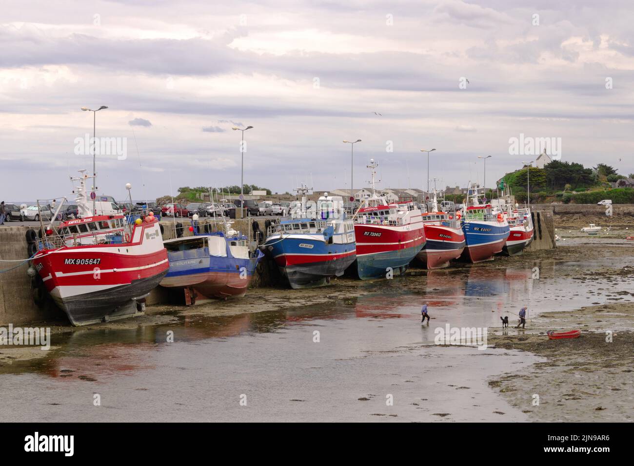 Photo horizontale de bateaux de pêche colorés à l'intérieur d'un port sec et de personnes pêchant autour de Roscoff, France Banque D'Images