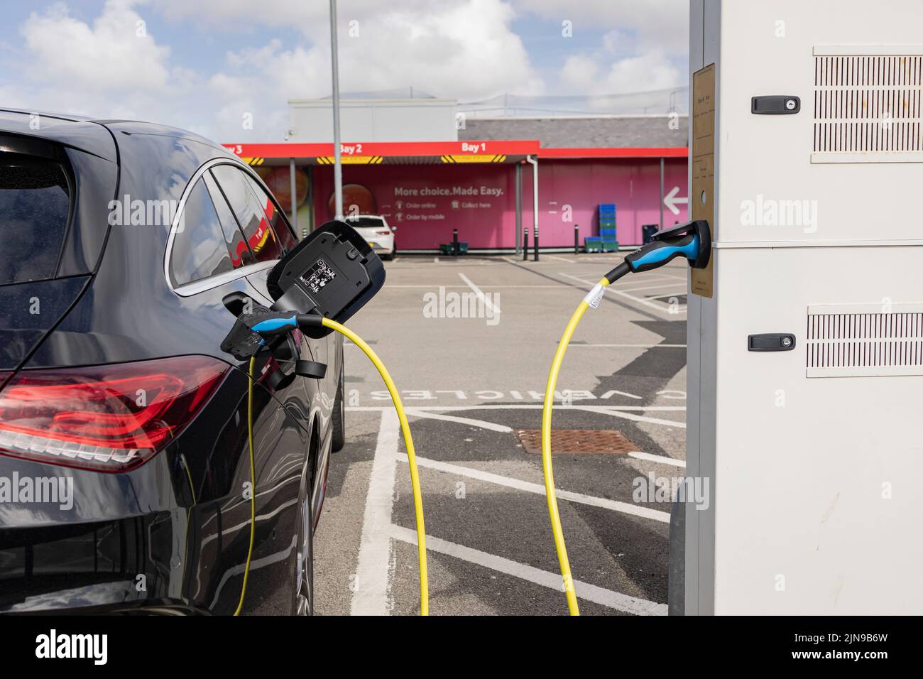 Charger la voiture électrique moderne sur le parking super magasin qui est possible l'avenir de l'automobile, la boutique et charge style de vie Banque D'Images