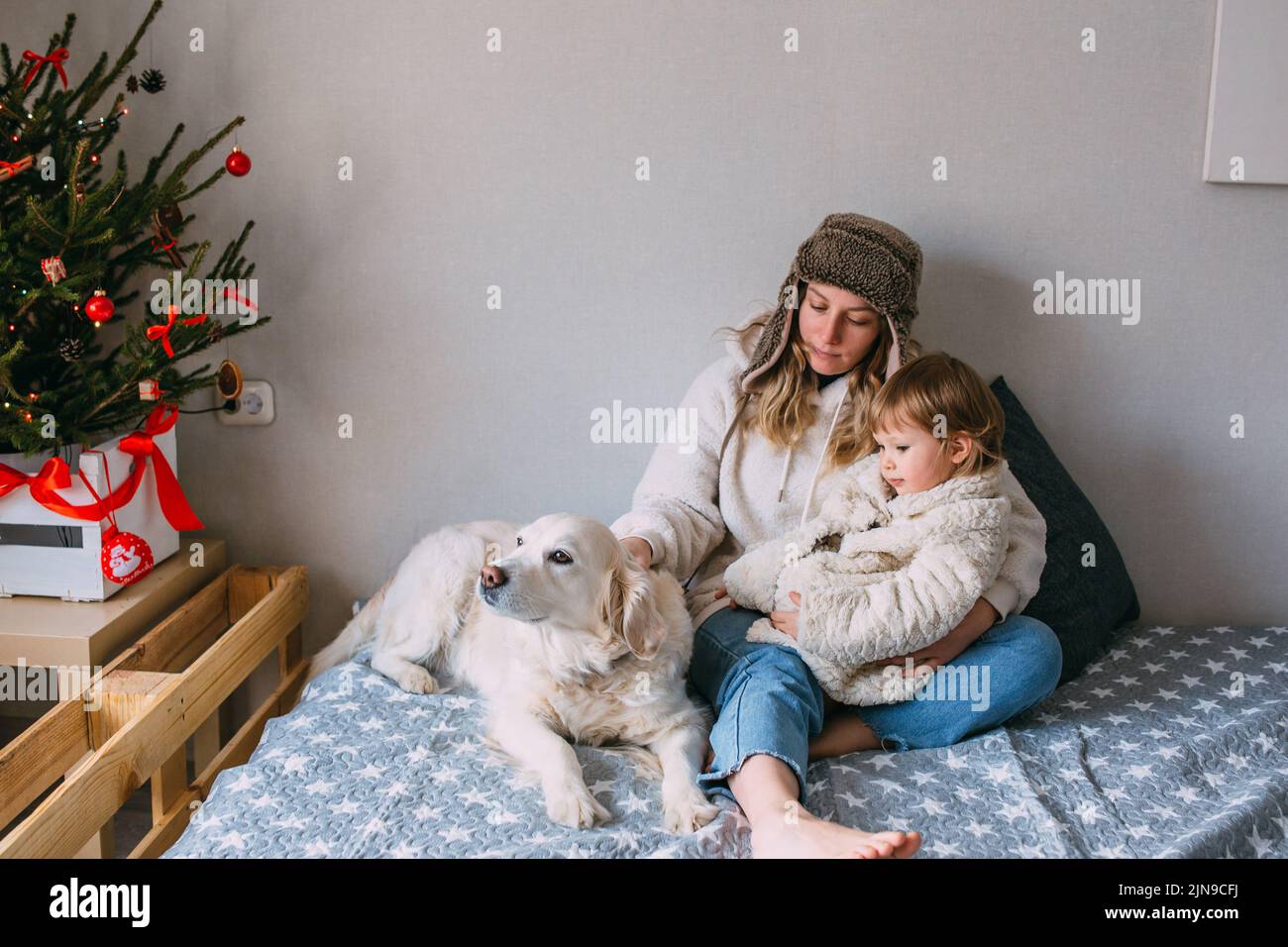 Maman et fille se câblent confortablement à la maison avec leur Labrador Retriever Banque D'Images