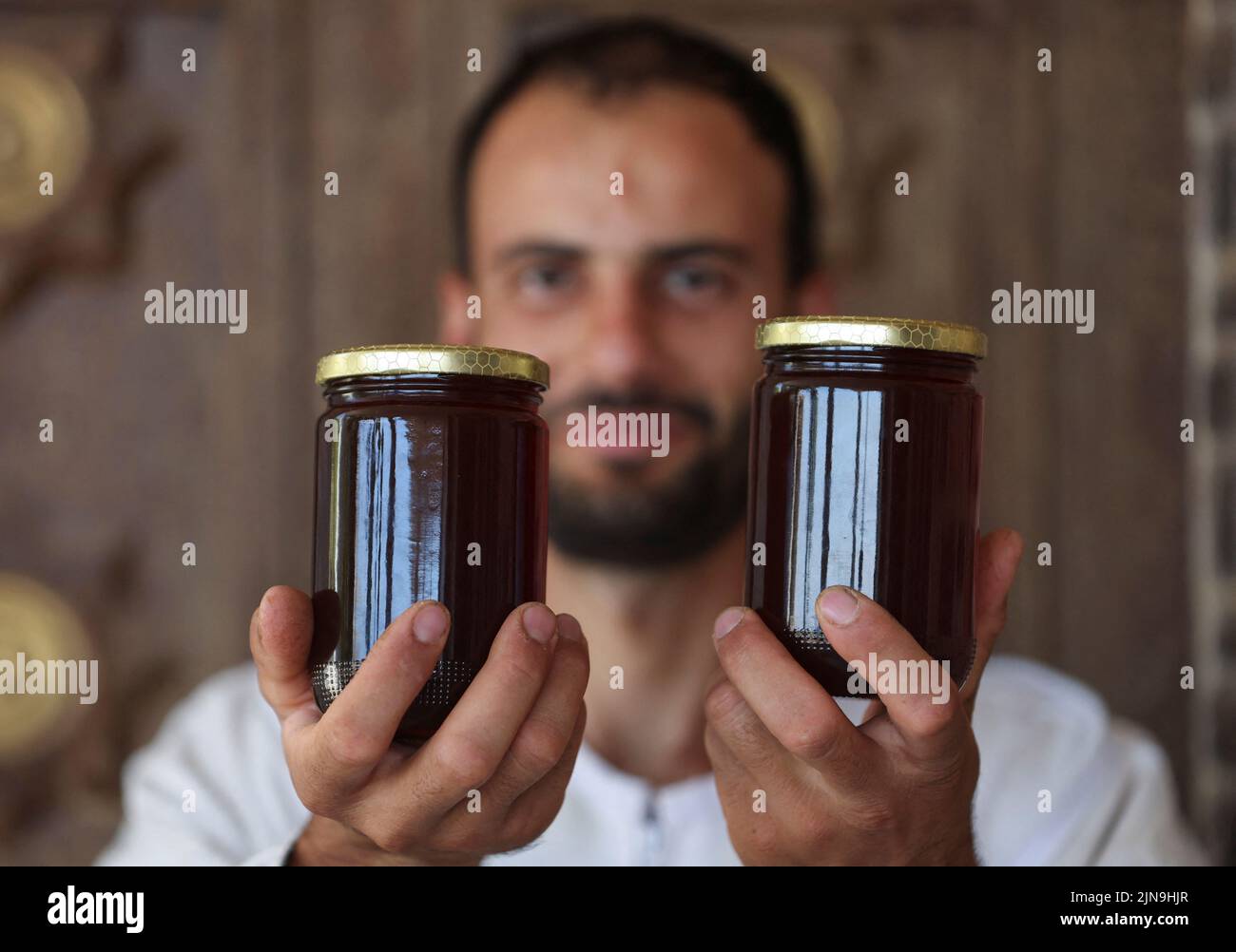 Mohamed Abdel Salam Nasrallah, apiculteur libanais et fabricant de miel, expose deux bocaux de miel dans le village Houla, près de la frontière avec Israël, au sud du Liban 28 juillet 2022. REUTERS/Aziz Taher Banque D'Images