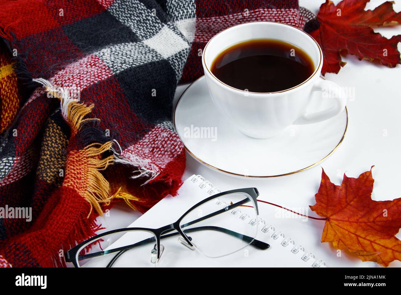 Concept Hello Autumn. Tasse de café expresso chaud et feuilles rouges tombées sur fond blanc. Un écossais chaud et une boisson chaude par temps froid. Copier l'espace. Banque D'Images