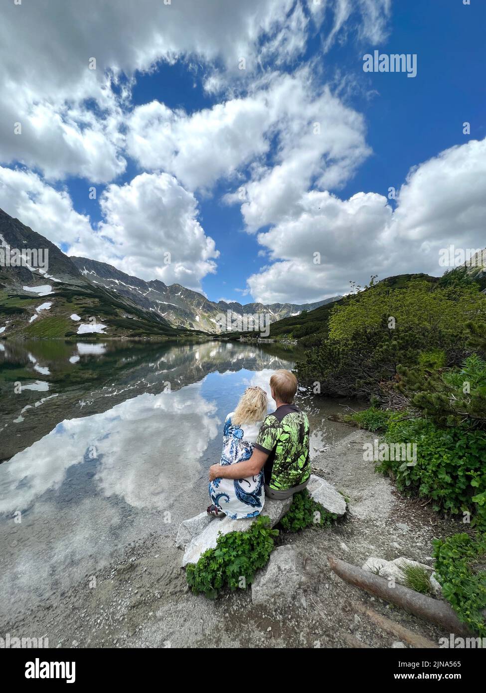 Vue arrière d'un couple assis près d'un lac de montagne, Zakopane, Pologne Banque D'Images