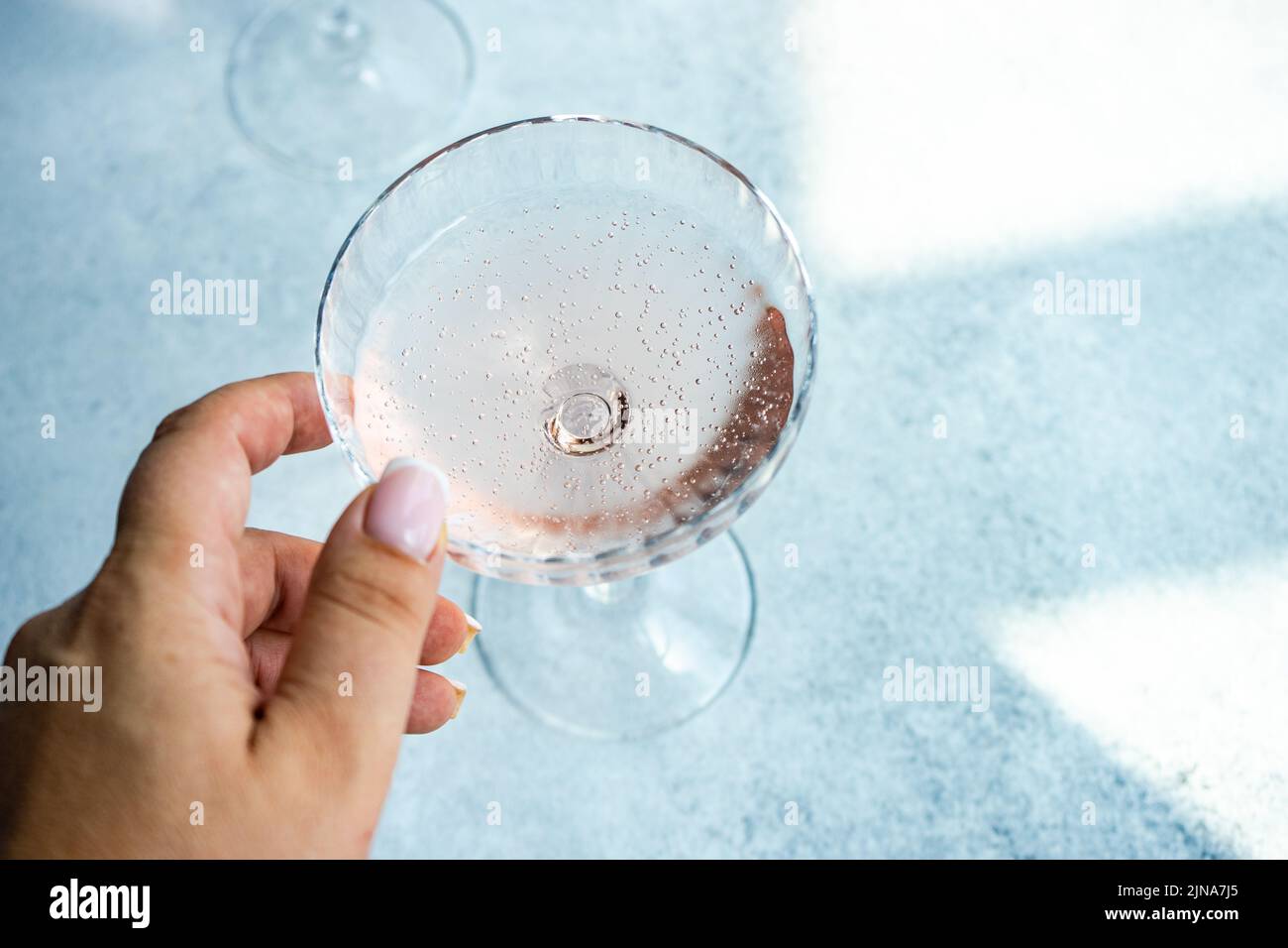 Femme qui se présente pour un verre de champagne rose Banque D'Images