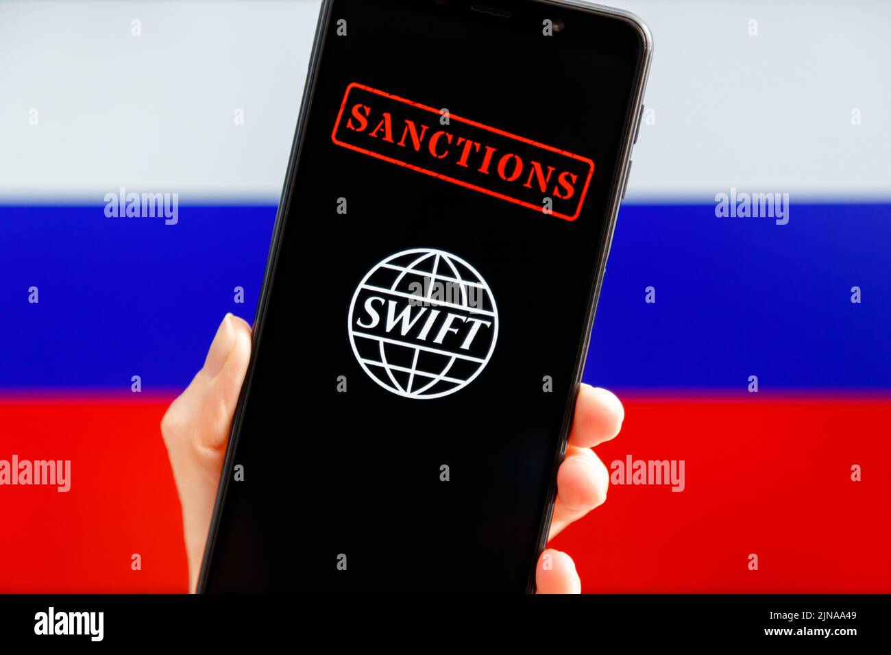 Ukraine, Kiev - février 23 2022 : portable avec logo SWIFT, sanctions et drapeau russe en arrière-plan. Sanctions contre la Russie, déconnexion du concept SWIFT. Banque D'Images