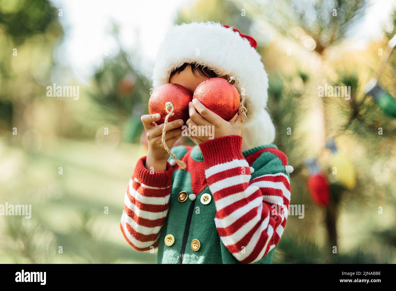 Noël en juillet. Enfant attendant Noël en bois en été. Portrait de garçon décorant arbre de noël. Vacances d'hiver et concept de gens. Joyeux Noël et joyeuses fêtes Banque D'Images