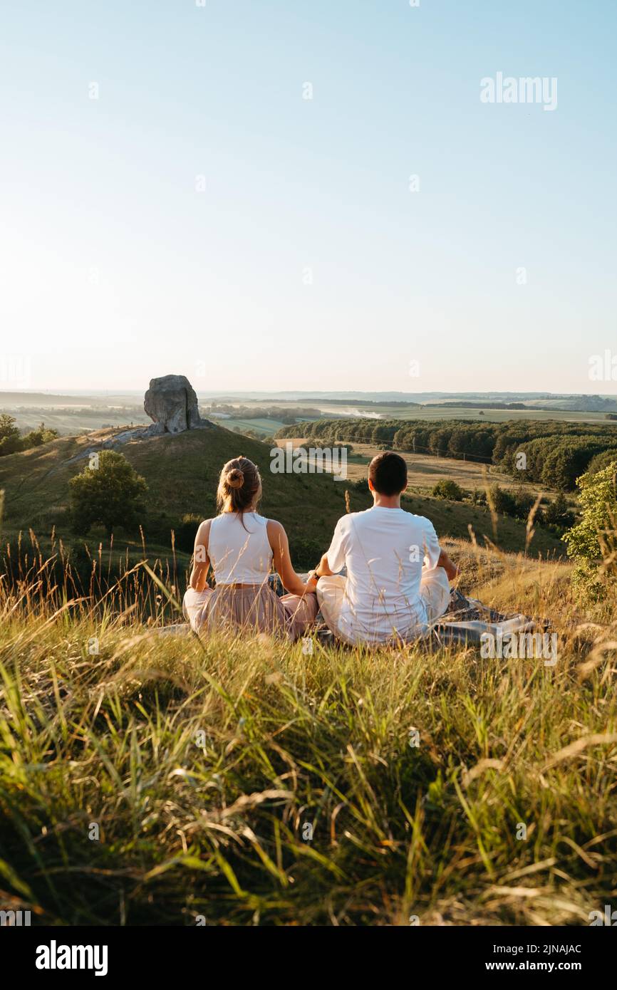 Homme et femme pratiquant le yoga et la méditation en plein air au coucher du soleil avec paysage pittoresque et nature Miracle Giant Stone sur le fond Banque D'Images