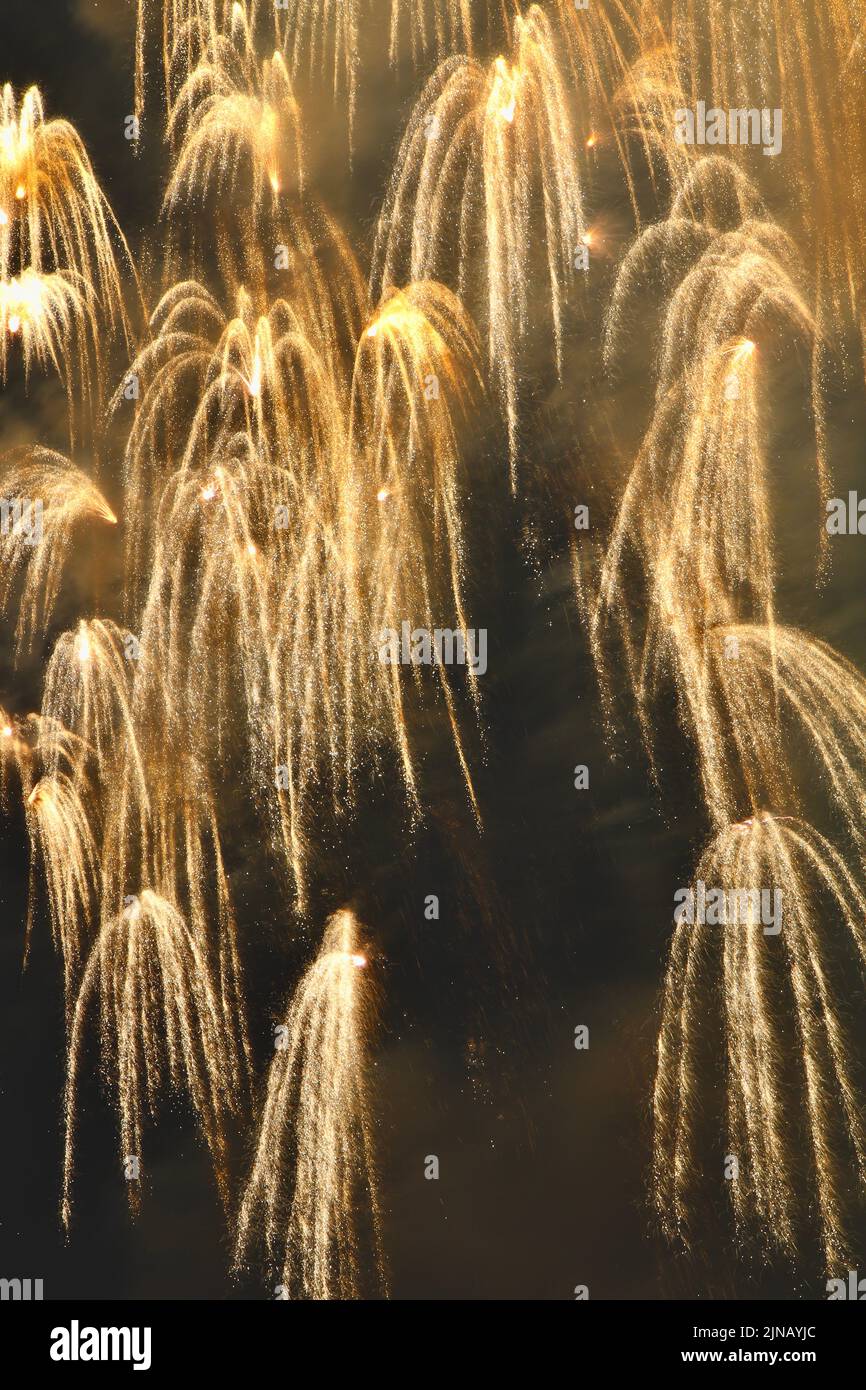 Longue exposition de feux d'artifice dorés créant une cascade dans le ciel nocturne. Banque D'Images