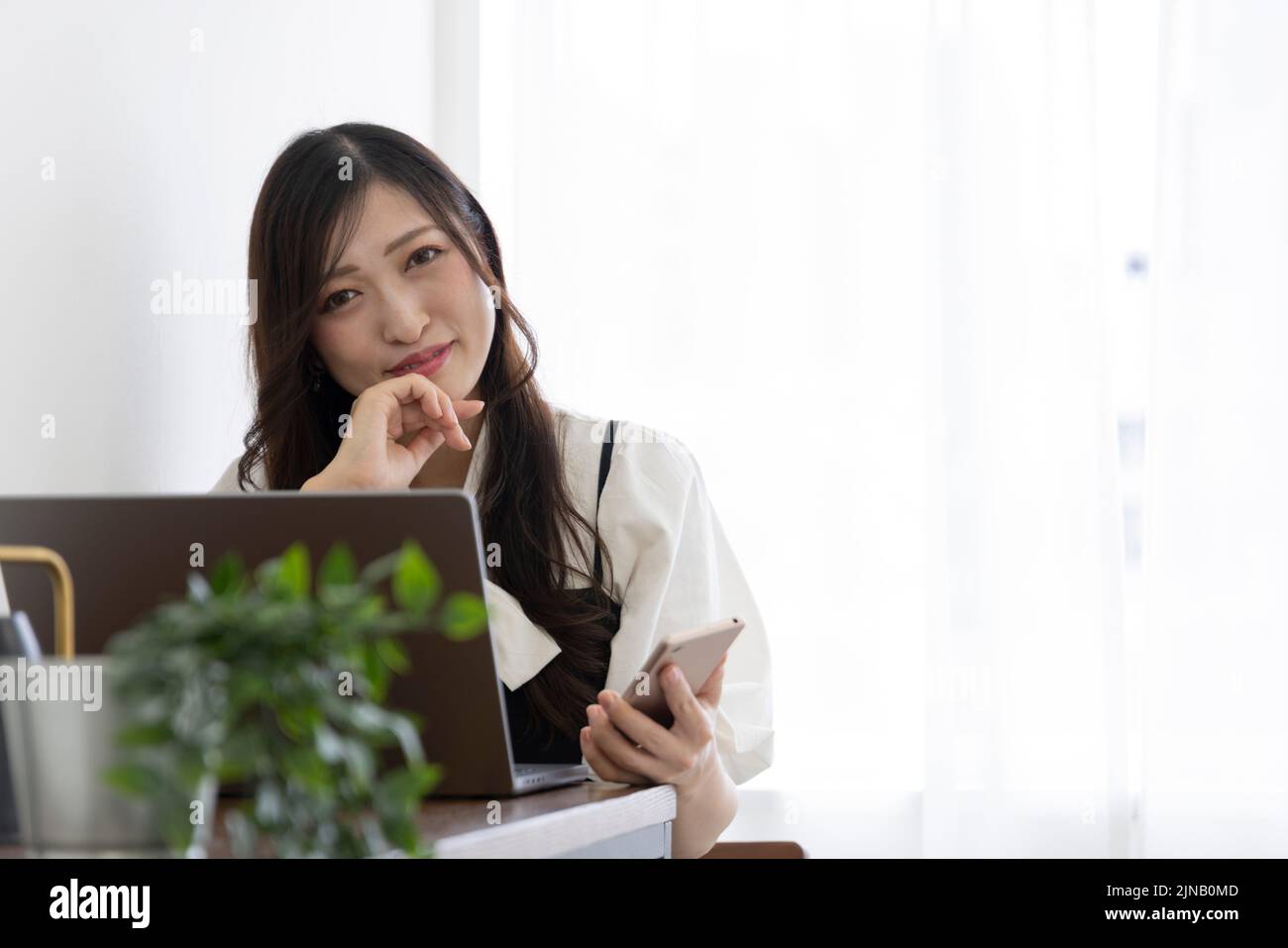 Une femme japonaise qui vérifie son smartphone par un travail à distance dans un petit bureau Banque D'Images