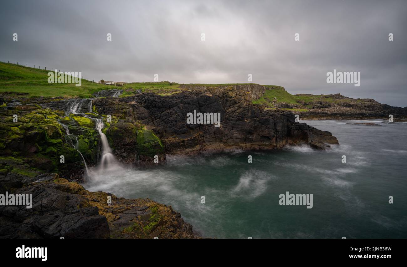 Une longue vue sur la côte irlandaise pittoresque et la cascade de Dunseverick en été Banque D'Images