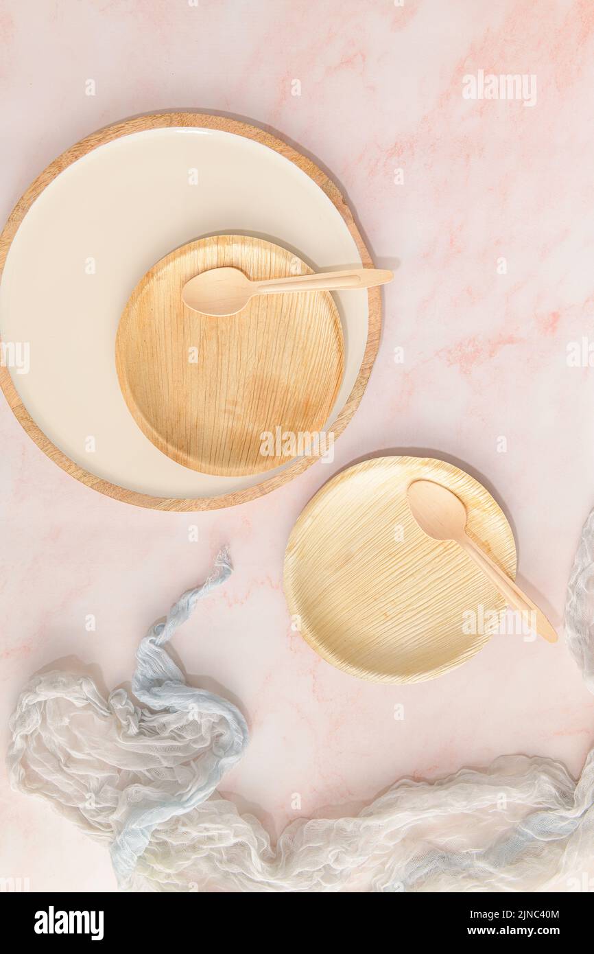 Assiettes à feuilles d'areca avec cuillères recyclables sur un comptoir de cuisine en marbre rose. Concept d'alimentation saine avec des préoccupations de durabilité environnementale. Banque D'Images