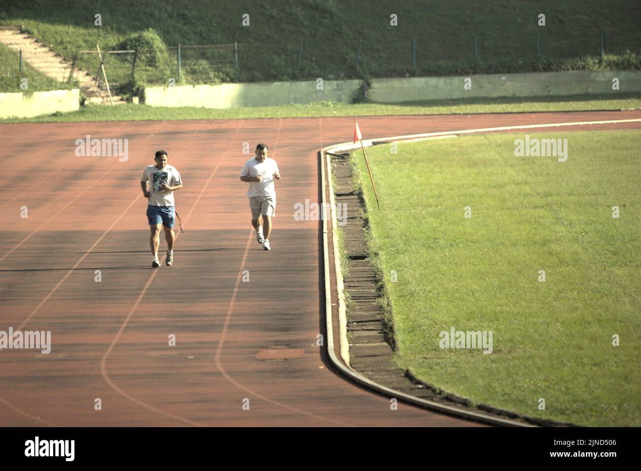 Des hommes qui font du jogging sur la piste athlétique du terrain de football de l'école de sport de Ragunan et du complexe sportif de Ragunan, Pasar Minggu, Jakarta, Indonésie. Banque D'Images