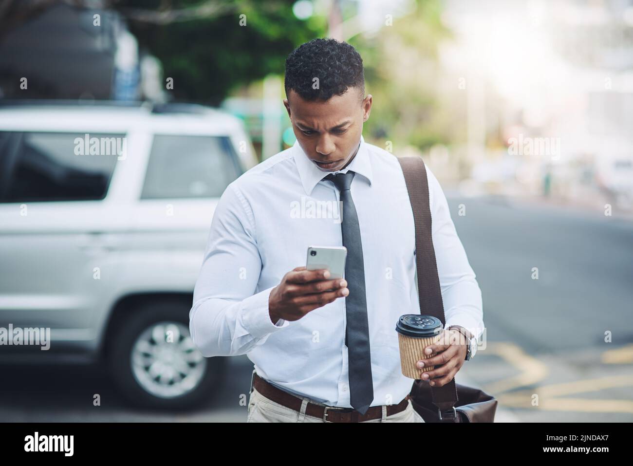 Il fait des affaires en déplacement. Un beau jeune homme d'affaires utilisant un téléphone portable dans la ville. Banque D'Images