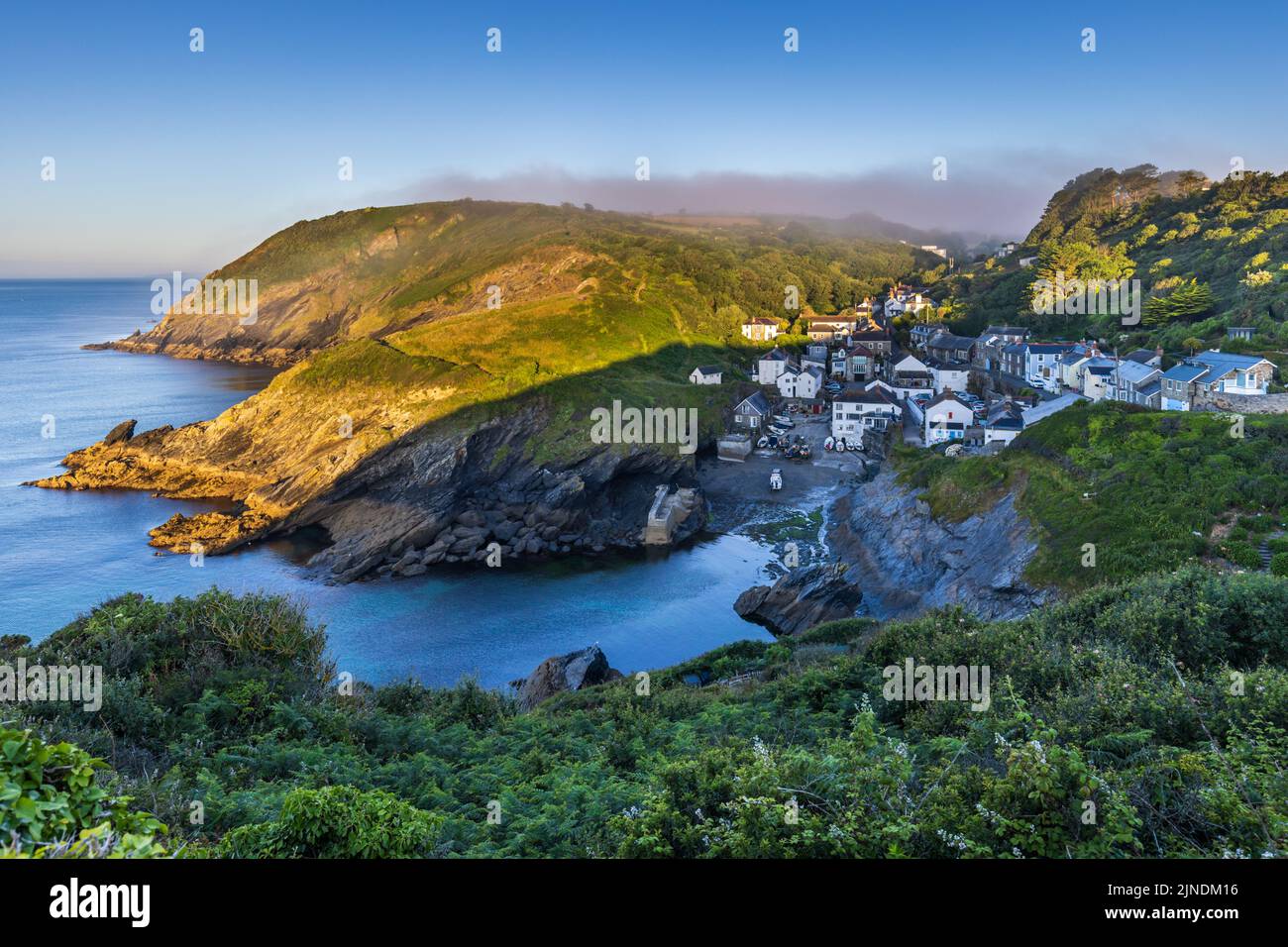 Vue sur le pittoresque village de pêcheurs de Portloe sur la côte sud de Cornwall depuis le South West Coast Path. Capturé peu après le lever du soleil. Banque D'Images