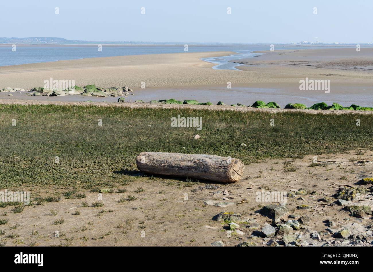 Flint s'étend sur la rivière Dee à marée basse avec un gros morceau de bois de flotté Banque D'Images