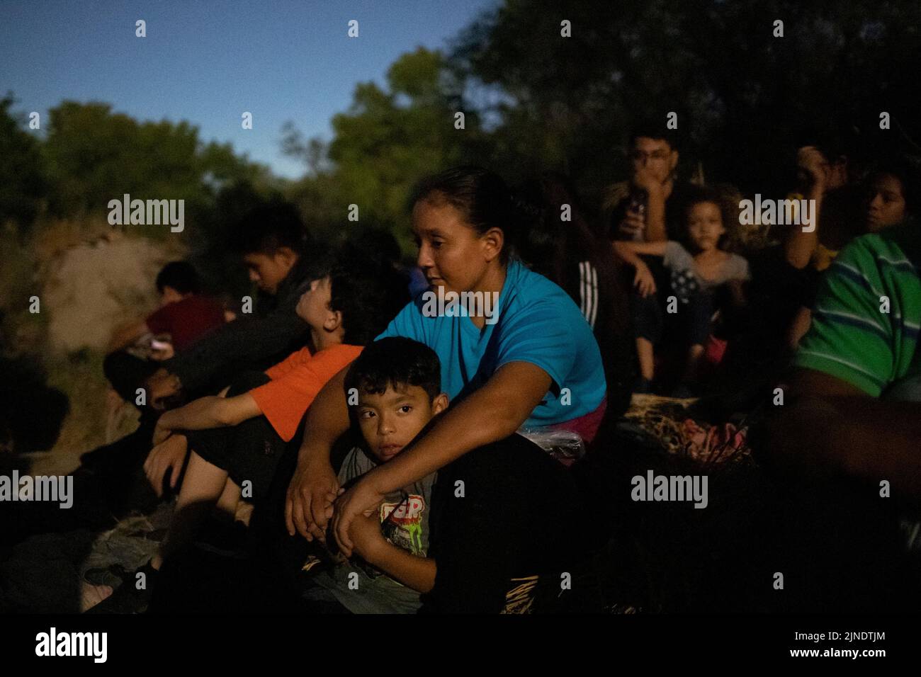 Les migrants demandeurs d'asile, dont Kimberly et son fils Derrick, 8 ans, d'El Salvador, sont vus dans la lumière ambiante depuis la lune, tandis qu'ils se reposent sur un sentier de migration après avoir traversé les États-Unis depuis le Mexique à Rome, le Texas, les États-Unis et le 10 août 2022. REUTERS/adrees Latif Banque D'Images