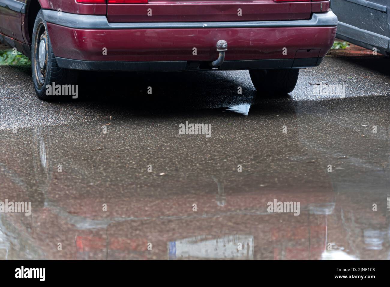flaques sur le trottoir avec un reflet d'une voiture garée, gros plan, route après la pluie Banque D'Images