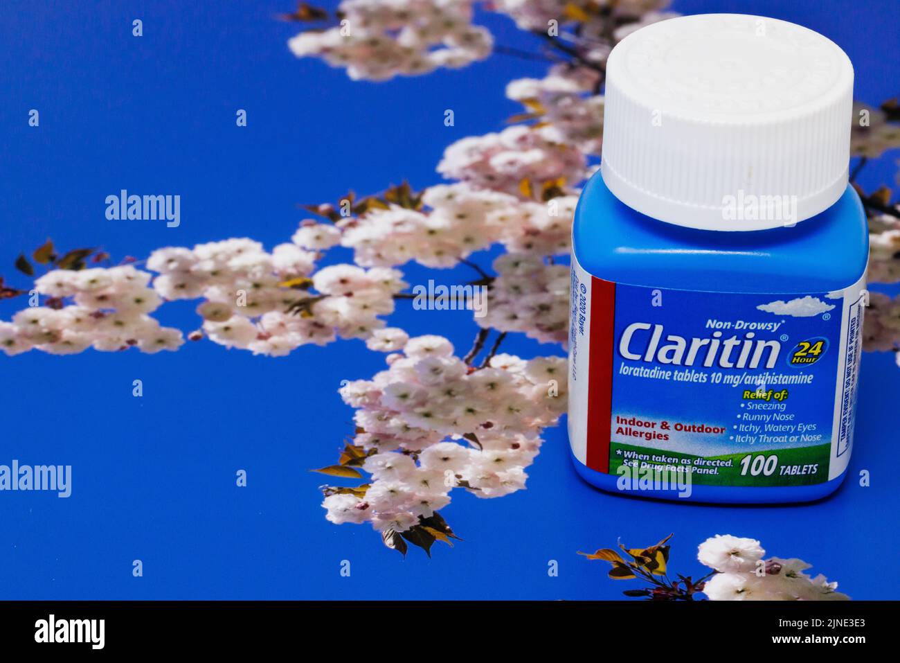 Contenant de comprimés de Claritin sur une surface à motif fleur et ciel bleu Banque D'Images