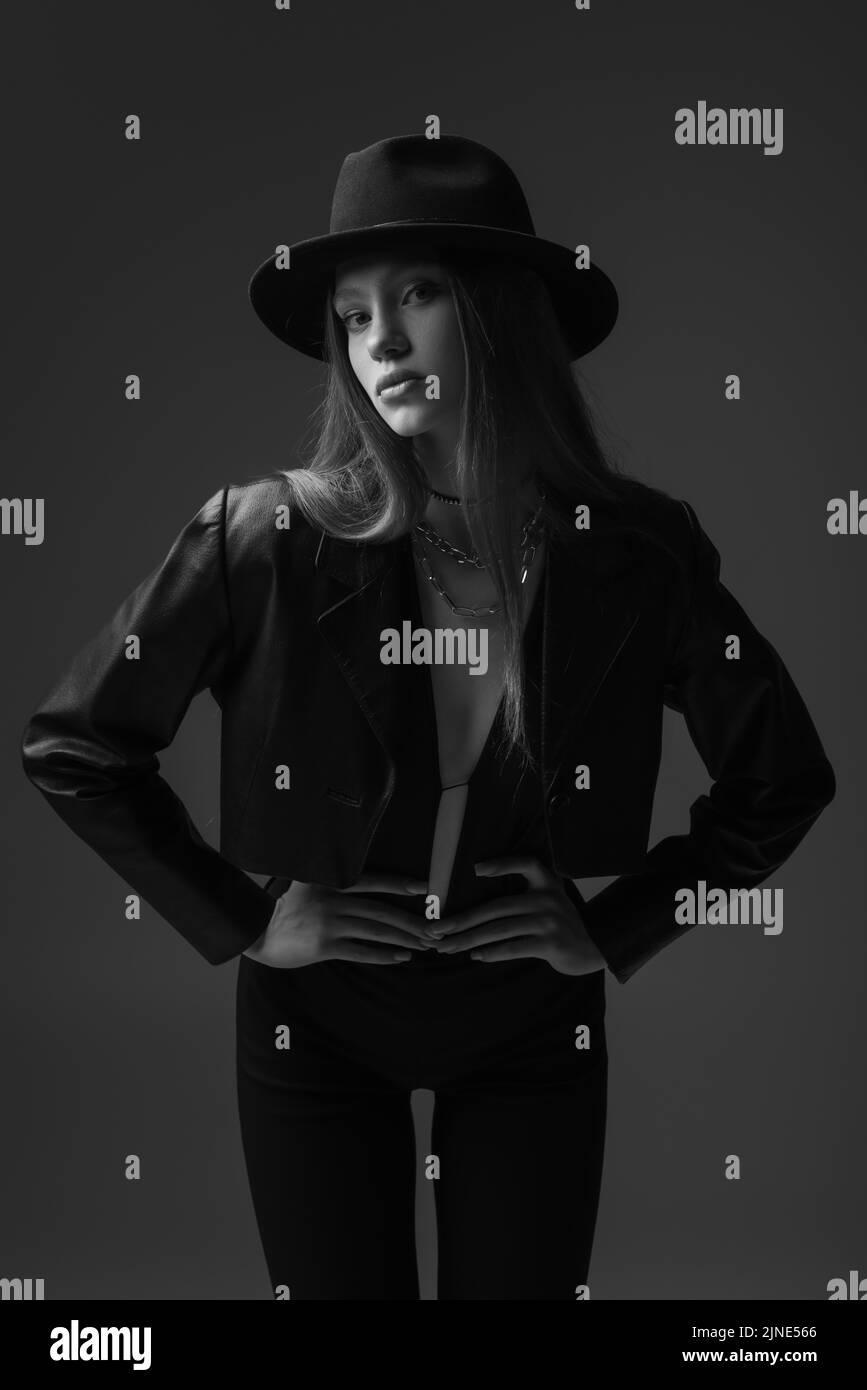 photo monochrome d'un mannequin adolescent dans un chapeau fedora posé avec les mains sur les hanches en studio Banque D'Images