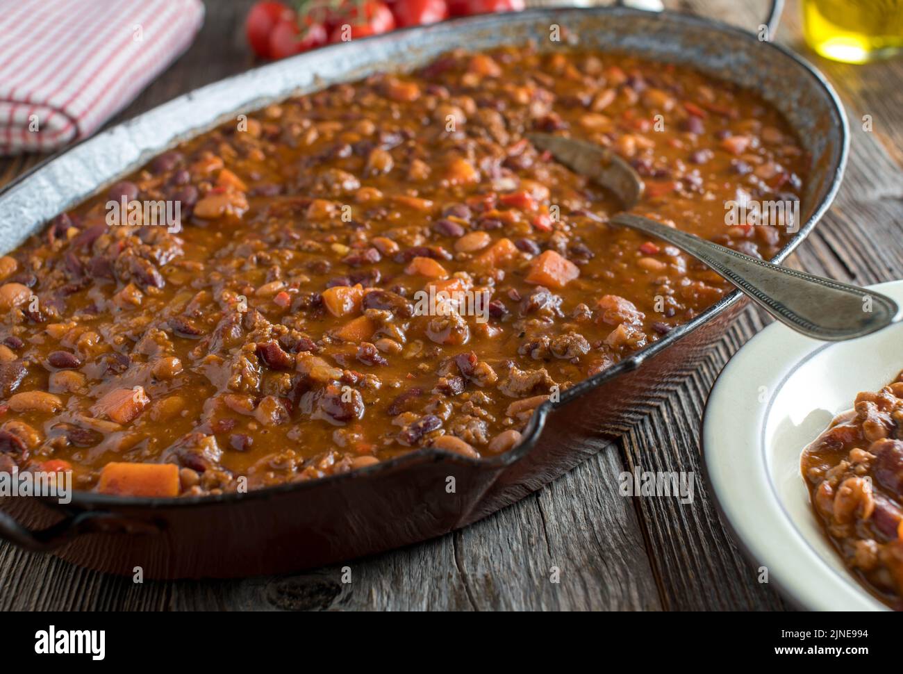 Ragoût de bœuf haché avec des haricots, des patates douces et des légumes - style Chili con carne dans une rôtissoire à l'ancienne sur une table en bois Banque D'Images
