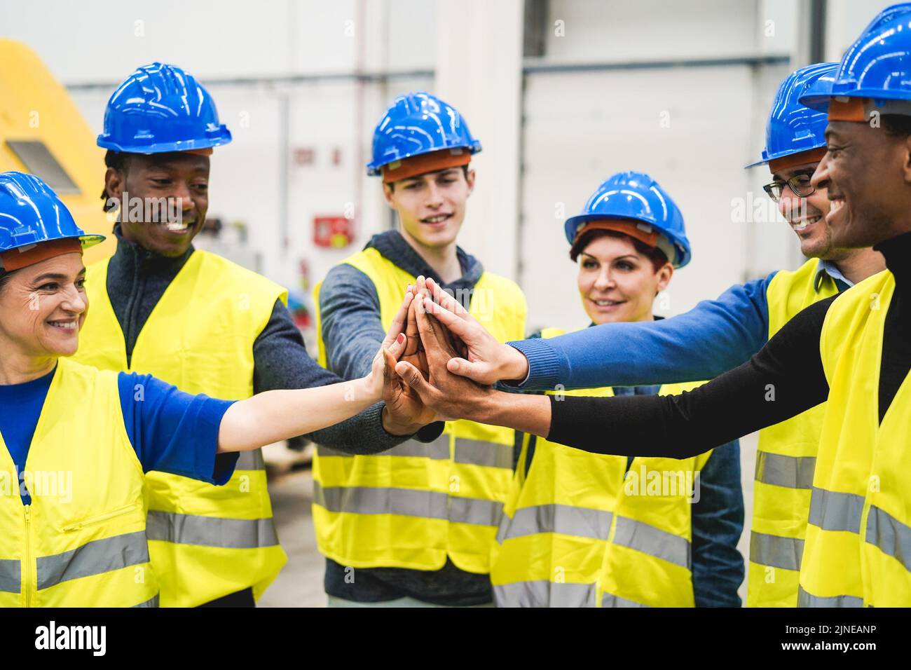 Les ingénieurs multiraciaux empilent les mains dans l'usine robotique - concentrez-vous sur les mains Banque D'Images