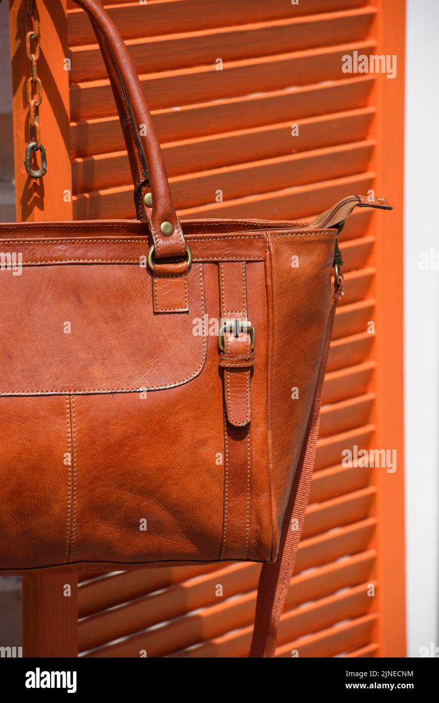 photo en gros plan d'un sac en cuir orange sur des stores en bois Banque D'Images