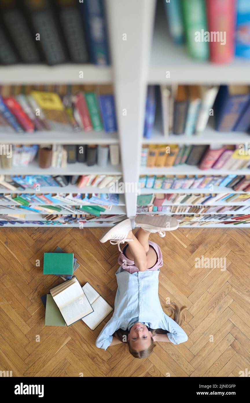 Adolescente gaie qui se repose dans la bibliothèque Banque D'Images