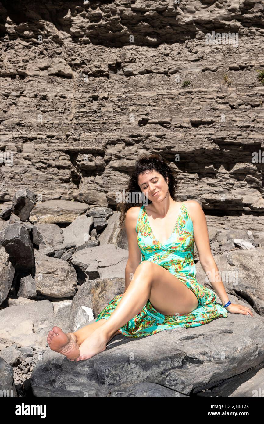 brunette femme assise sur quelques rochers avec une robe verte Banque D'Images