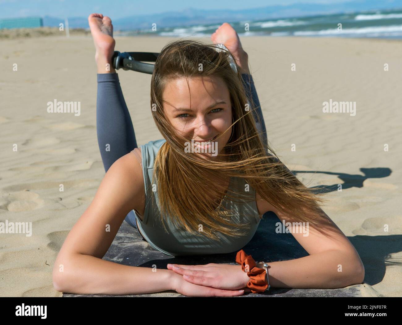 jeune athlète posant avec pilates anneau sur la plage Banque D'Images