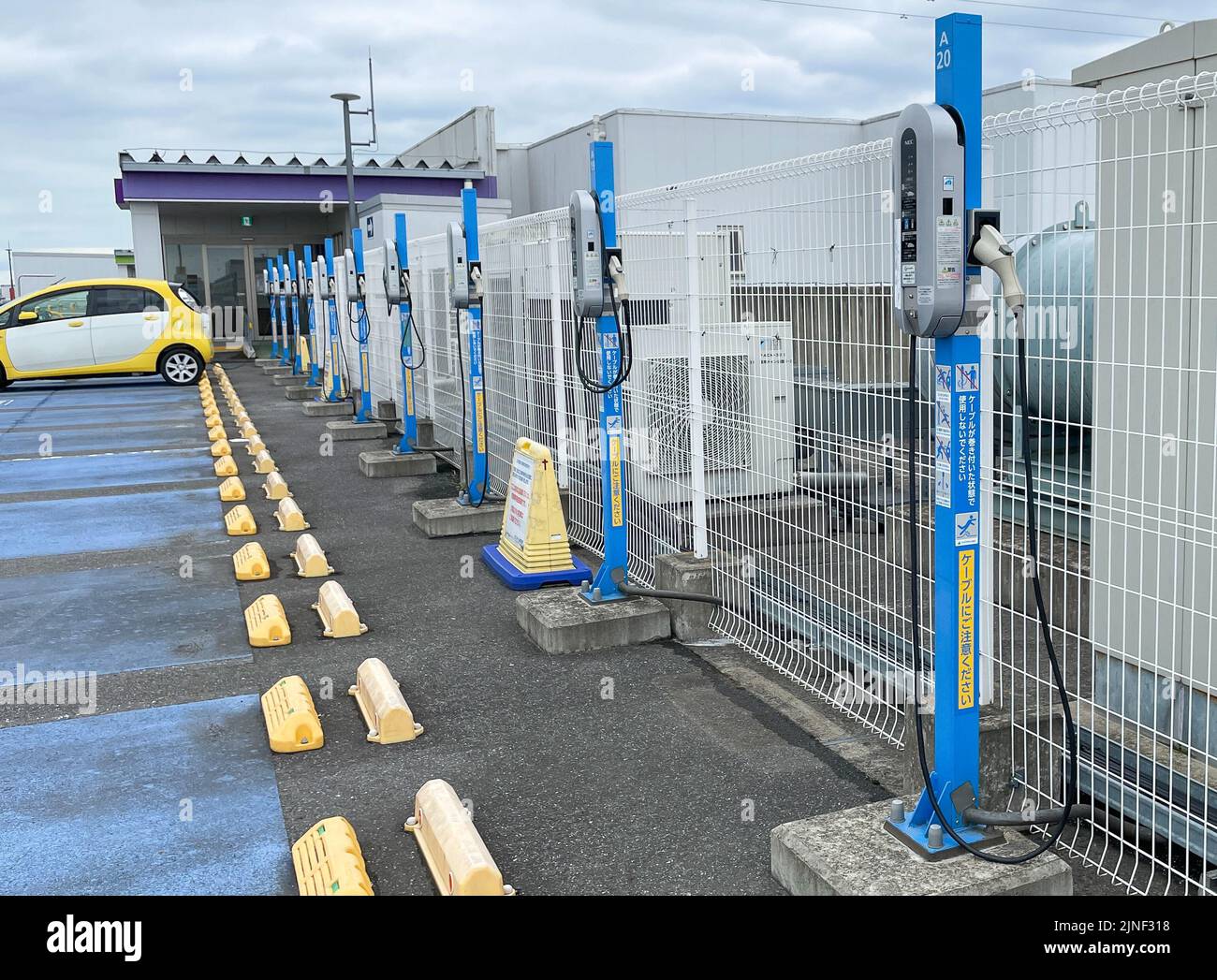 Une rangée de chargeurs de véhicules électriques standard NEC Corp. Au-dessus d'un parking sur le toit d'un centre commercial EON avec une seule voiture chargée à l'un des stans Banque D'Images