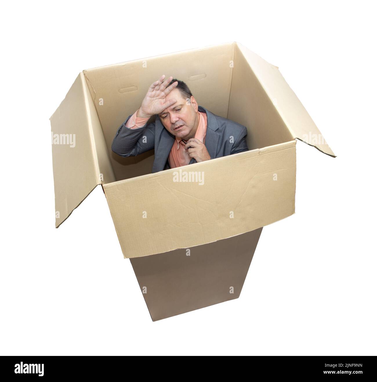 Homme stressé dans un costume debout à l'intérieur d'une boîte en carton, isolé sur fond blanc Banque D'Images