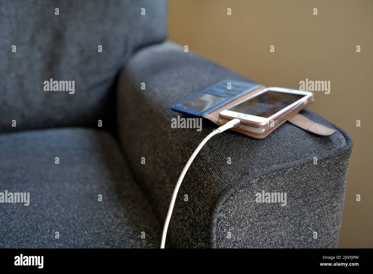 téléphone mobile se recharge sur le bras de la chaise à l'intérieur de la maison hertfordshire angleterre Banque D'Images