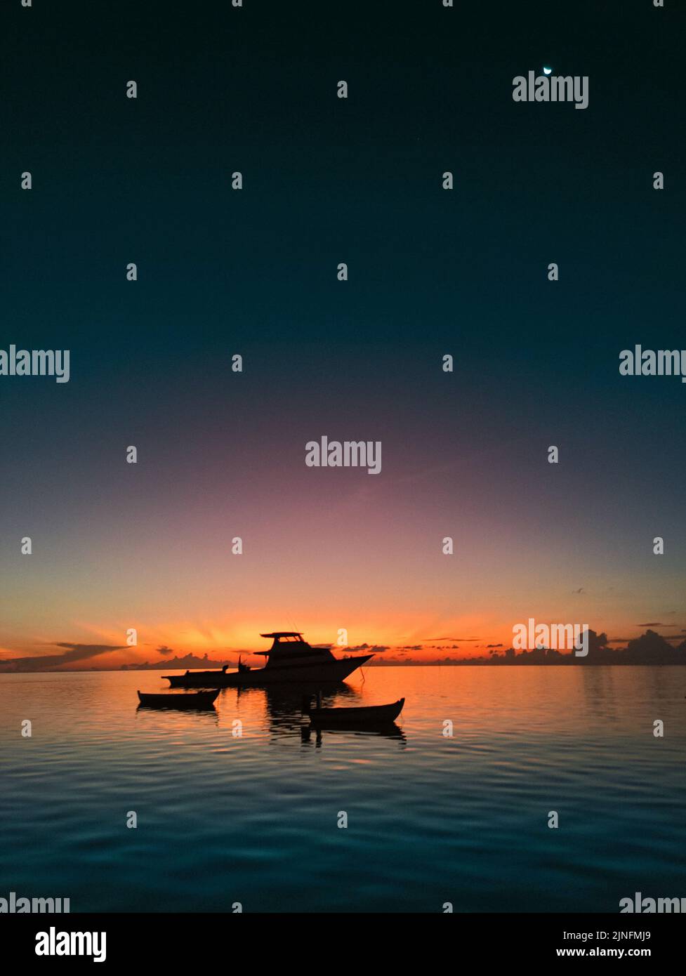 Magnifique coucher de soleil orange sur yacht et petits bateaux en mer. Le ciel coloré se reflète sur la surface lisse de l'eau Banque D'Images