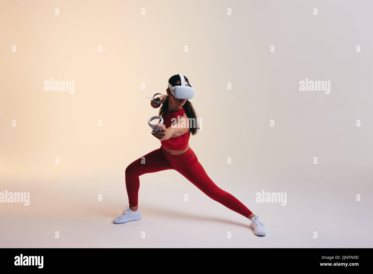 Sportswoman jouant à un jeu de fitness avec des manettes de jeu. Jeune femme active effectuant des exercices de formation en réalité virtuelle. Jeune femme sportive lasse Banque D'Images