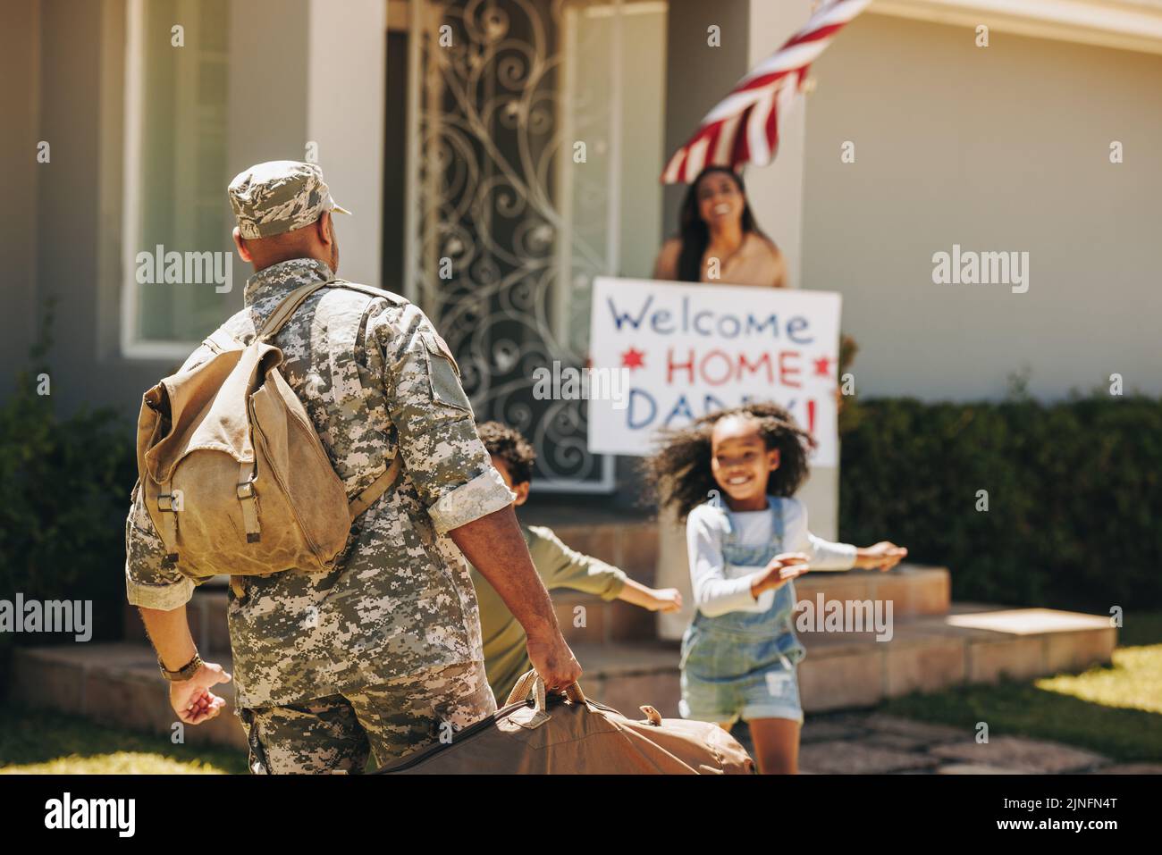 Accueillir papa de l'armée. Un père militaire reçoit un accueil chaleureux de sa femme et de ses enfants à la maison. Soldat américain revenant à sa famille à l'afte Banque D'Images