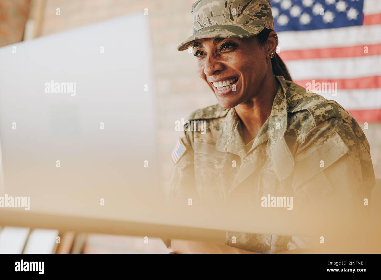 Une femme heureuse sourit joyeusement tout en discutant vidéo avec sa famille sur un ordinateur portable. Une militaire américaine qui communique avec ses proches Banque D'Images