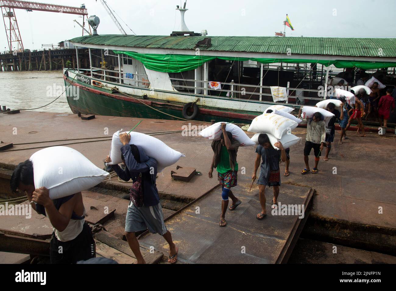 Yangon. 11th août 2022. Les travailleurs déchargent des sacs de riz d'un cargo à une jetée à Yangon, au Myanmar, le 11 août 2022. Selon le ministère du Commerce, les recettes d'exportation agricoles du Myanmar ont diminué de 1,25 pour cent pour s'établir à environ 1,27 milliards de dollars américains par rapport à l'année précédente au cours des quatre premiers mois de l'exercice 2022-2023. Le pays de l'Asie du Sud-est a changé son année fiscale, passant d'octobre-septembre à avril-mars à partir de cette année. Credit: Myo Kyaw SOE/Xinhua/Alay Live News Banque D'Images