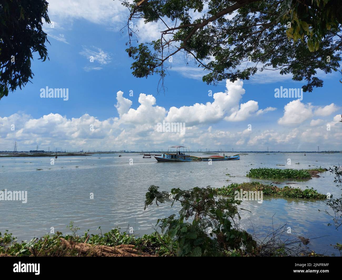 Les bateaux sur la rivière Turag contre un ciel nuageux Banque D'Images