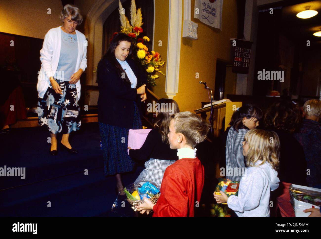 Église méthodiste les enfants donnent de la nourriture de récolte au Harvest Festival Surrey, Angleterre Banque D'Images