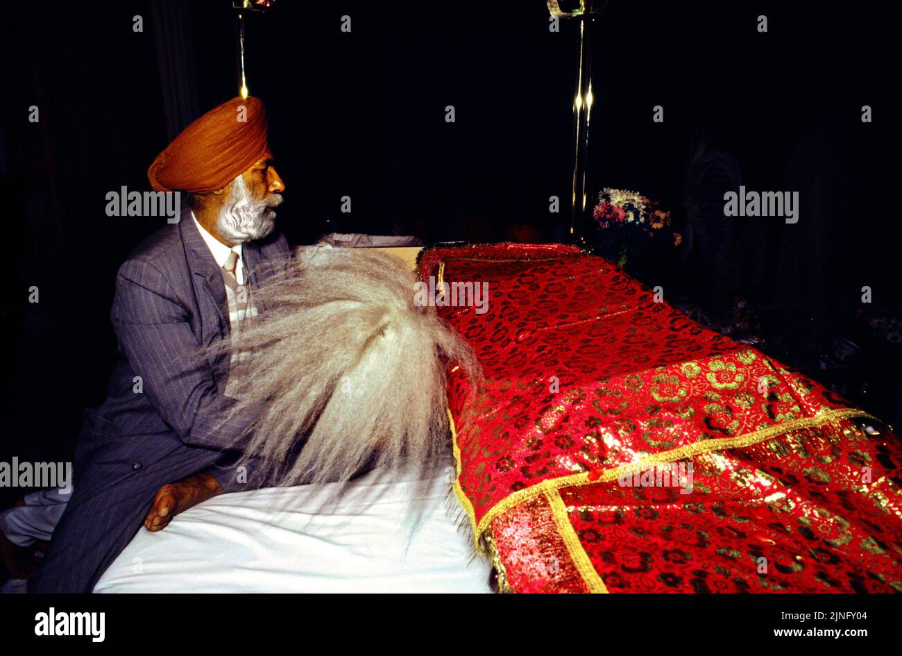 Southall London England Man Reading The Sri Guru Granth Sahib & Romalla Cloth on top tenant un Chauri à Gurdwara Banque D'Images
