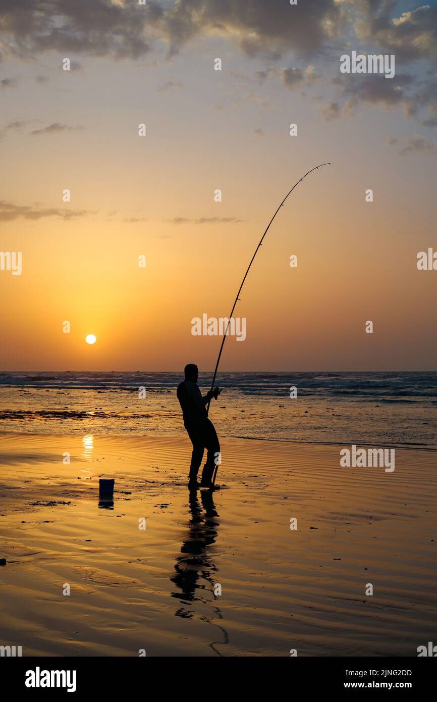 Un Fisher tenant son crochet avec sa tige de pêcheur avec un beau coucher de soleil dans la ville de Laayoune Banque D'Images Un Fisher tenant son crochet avec sa tige de pêcheur avec un beau coucher de soleil dans la ville de Laayoune Banque D'Images