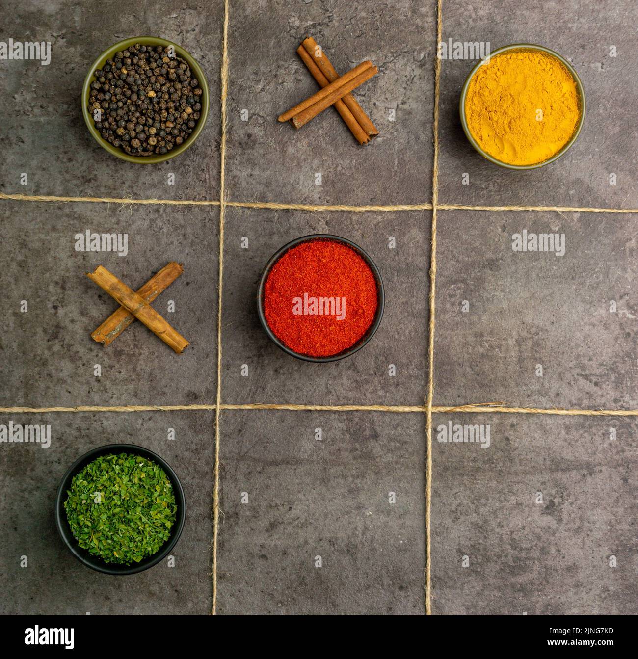 Diverses épices (poudre de poivron rouge, poudre de curcuma, poivre noir, feuilles de persil séché et cannelle) avec un concept de Bingo unique Banque D'Images