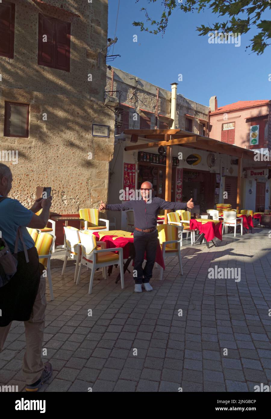 L'homme demande d'être photographié sur son propre téléphone par un passant. La vieille ville de Rhodes. Grèce, Dodécanèse. Scène de rue de l'île de Rhodes... Banque D'Images