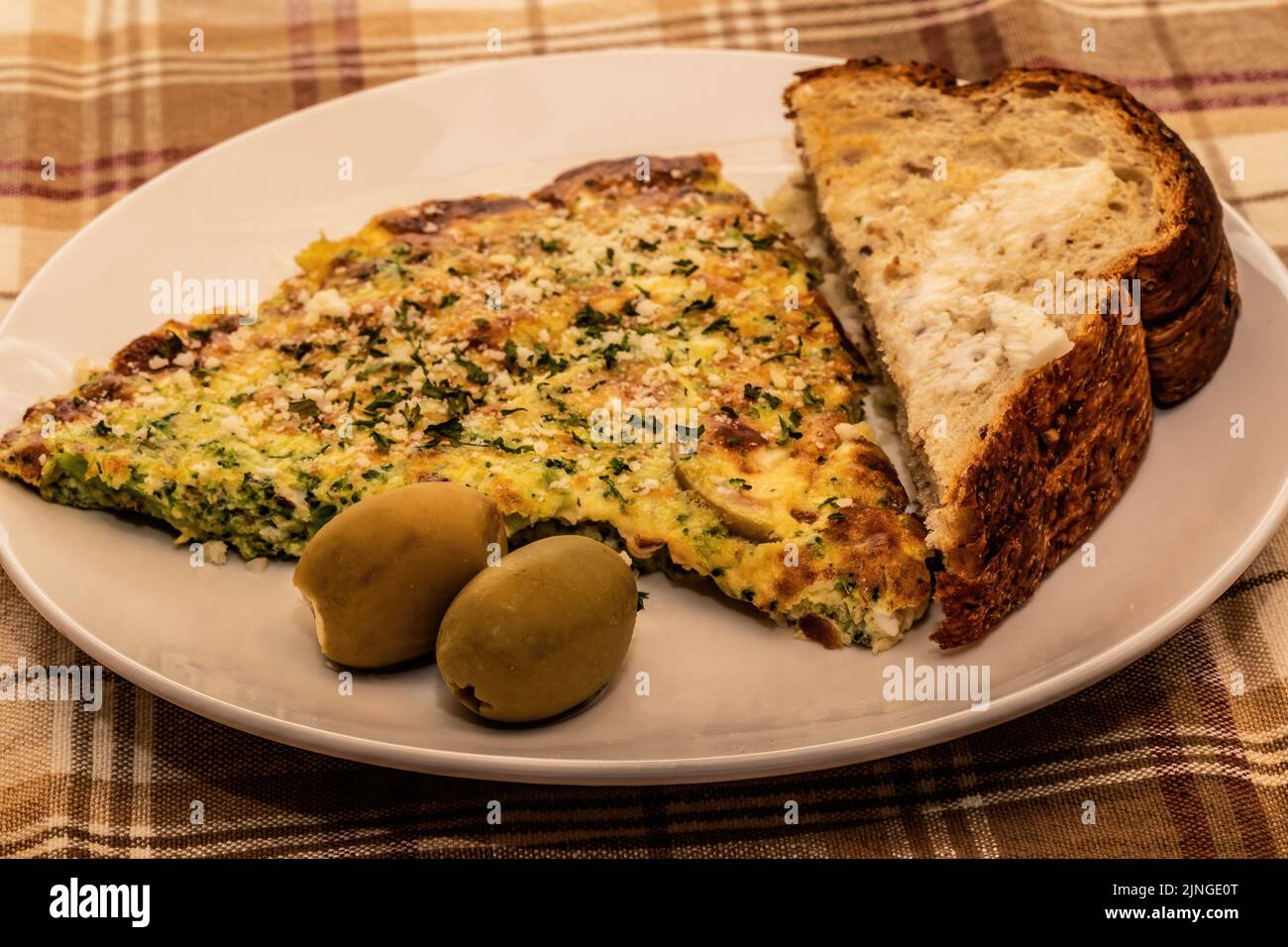 Omelette méditerranéenne au brocoli et au fromage avec olives vertes farcies au fromage Feta et pain Siebenfelder grillé. Banque D'Images
