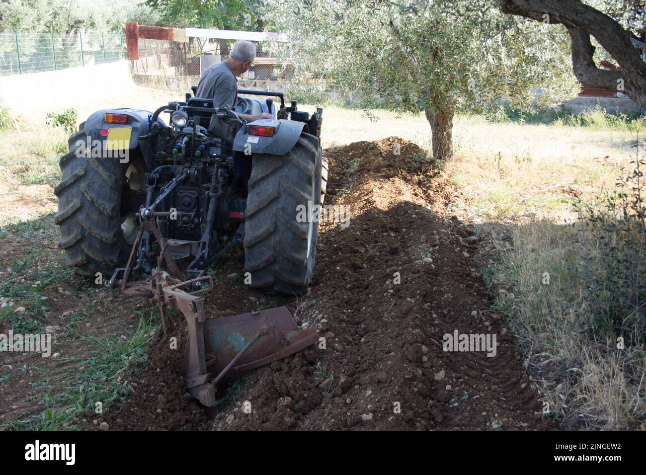Photo d'un agriculteur âgé qui débarque avec son tracteur. Travaux agricoles et labour Banque D'Images
