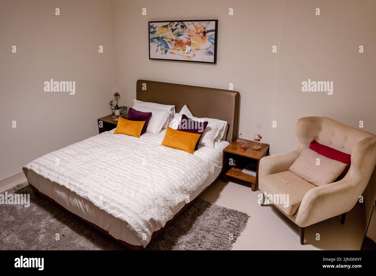 Une petite chambre avec un lit, une table de nuit et une chaise dans un style minimaliste Banque D'Images