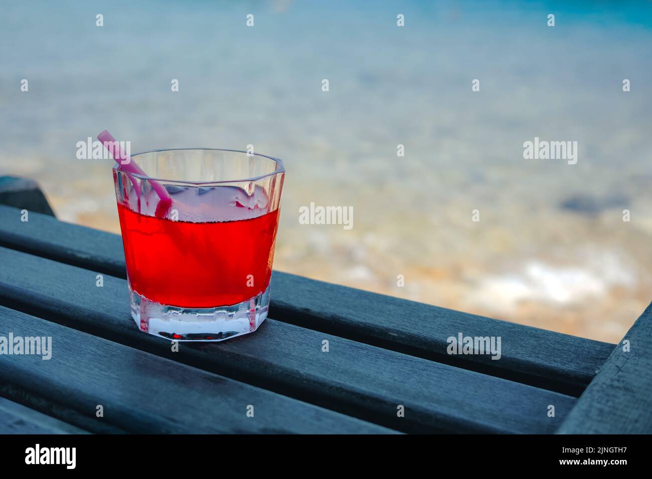 Cocktail rouge dans un verre sur une table en bois au café de la plage. Banque D'Images
