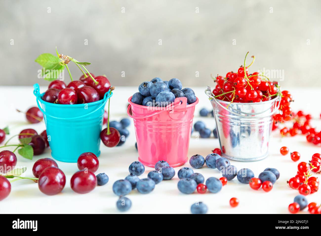 Mélanger les baies fraîches dans de petits seaux. Papier peint d'été juteux. Banque D'Images