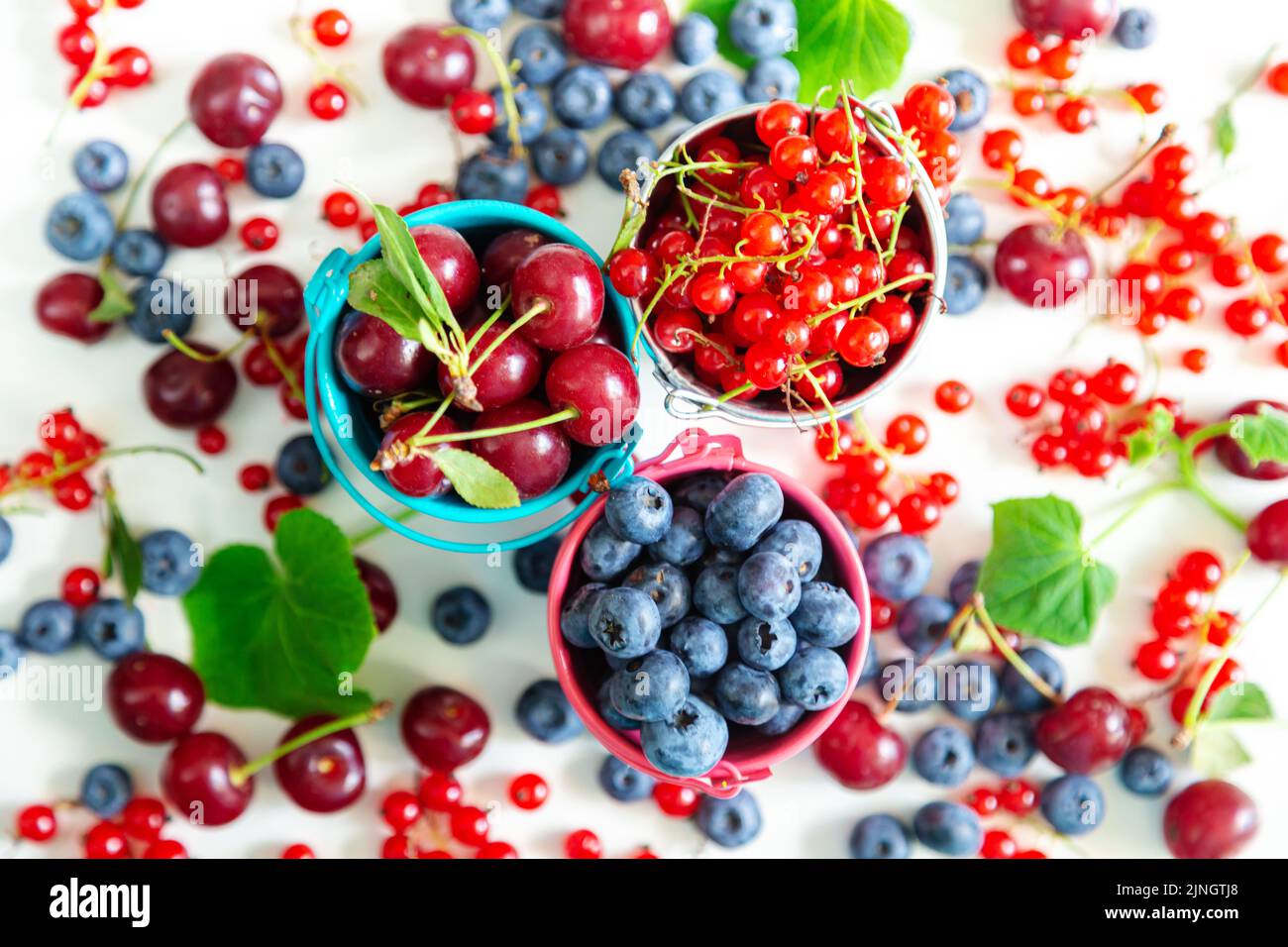 Mélanger les baies fraîches dans de petits seaux. Vue de dessus. Papier peint d'été juteux. Banque D'Images