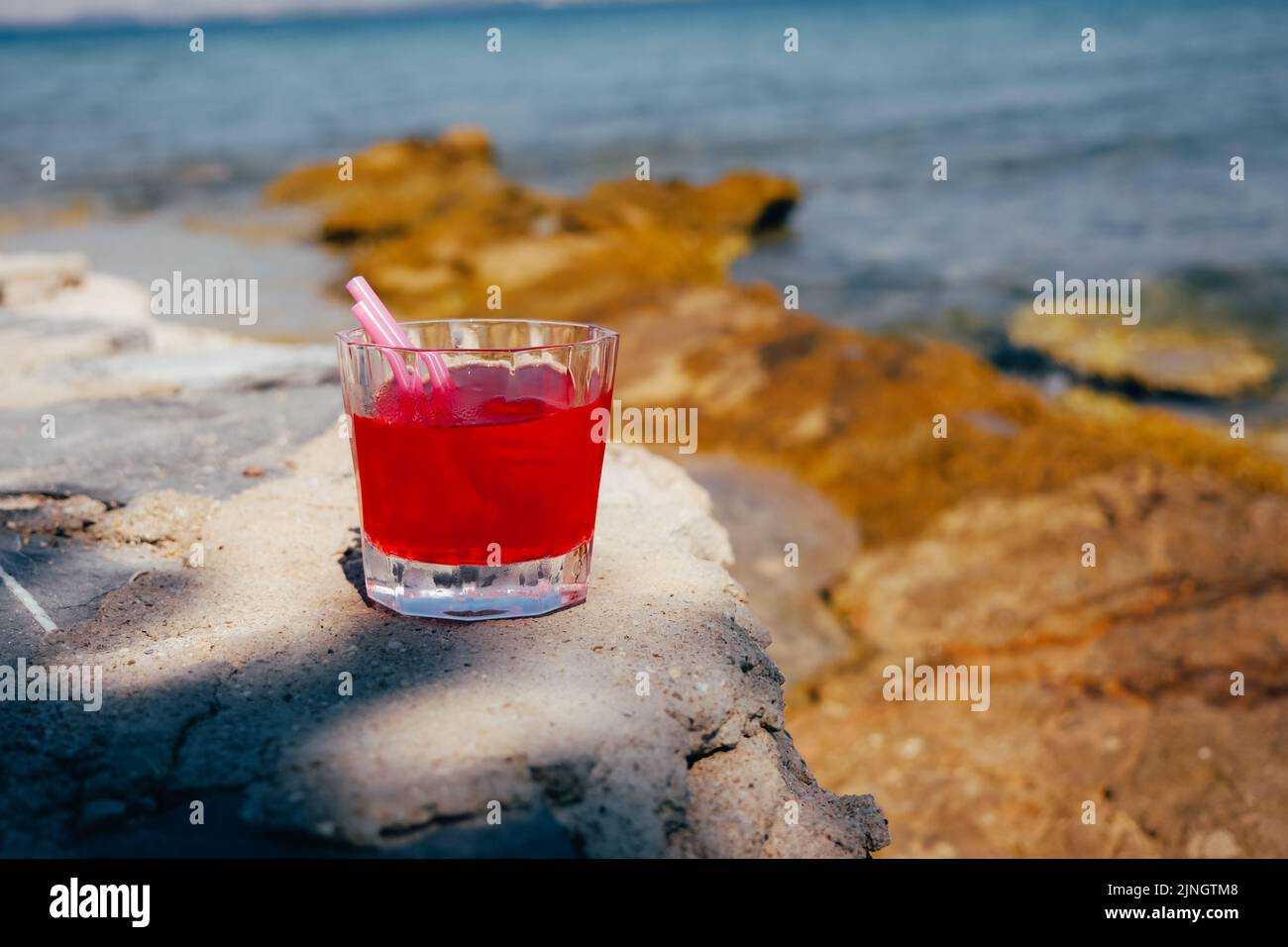 Cocktail rouge dans un verre sur une table en bois au café de la plage. Banque D'Images