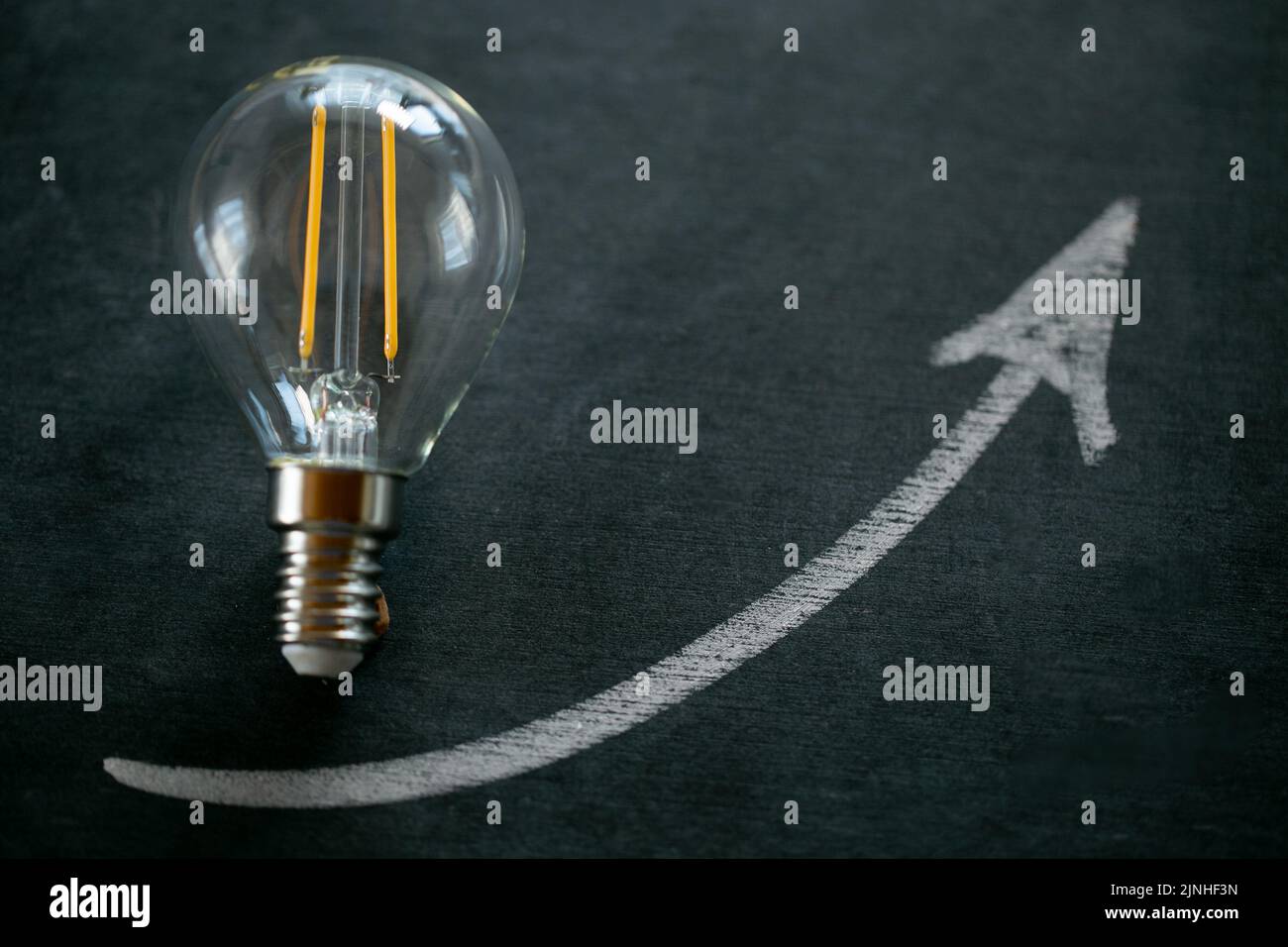 Prix de l'électricité.ampoule et de l'arrowon sur un tableau noir de craie.coût de l'électricité.crise de la production d'énergie.augmentation du coût de la lumière et de la chaleur Banque D'Images